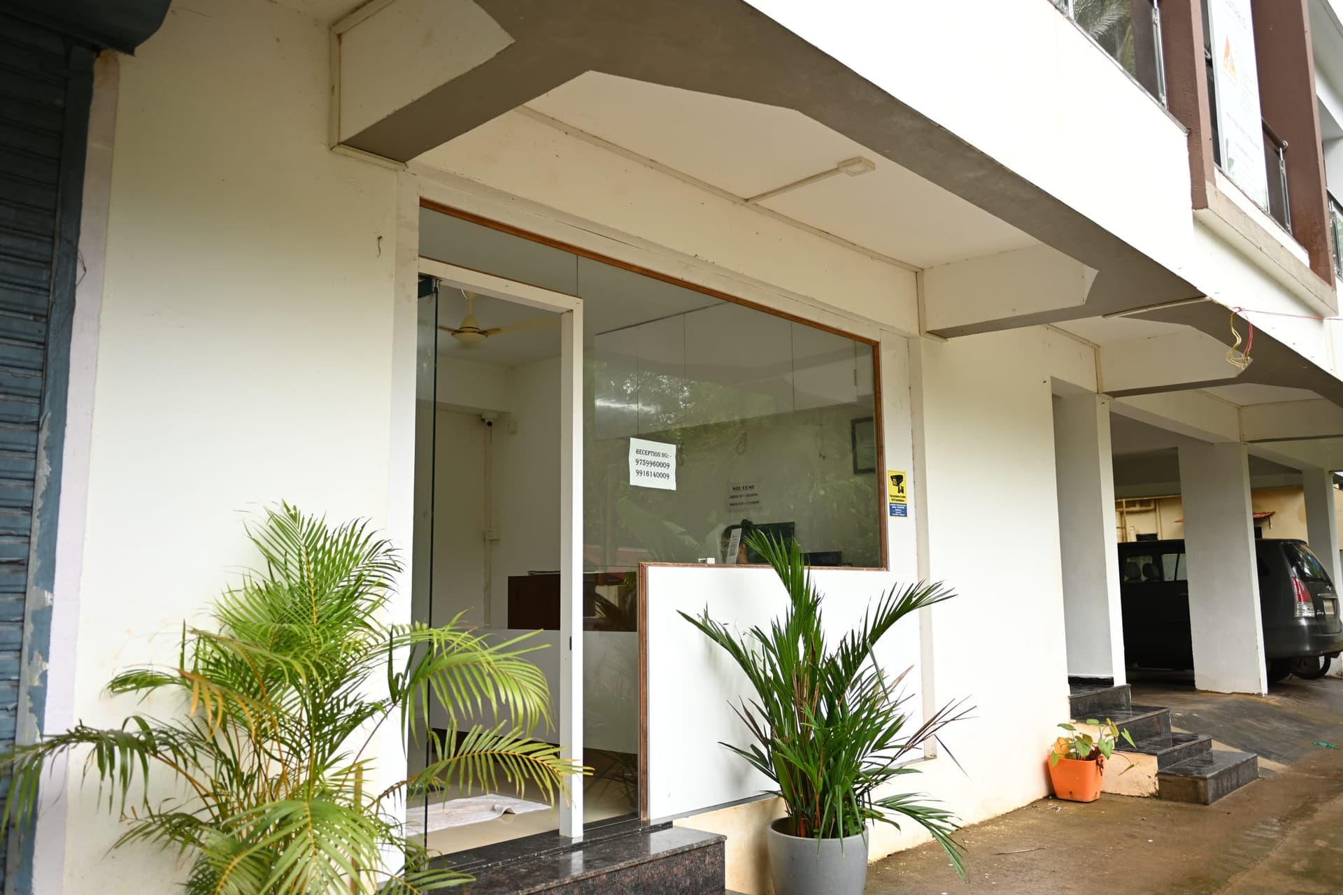 The glass door to reception with potted palms either side