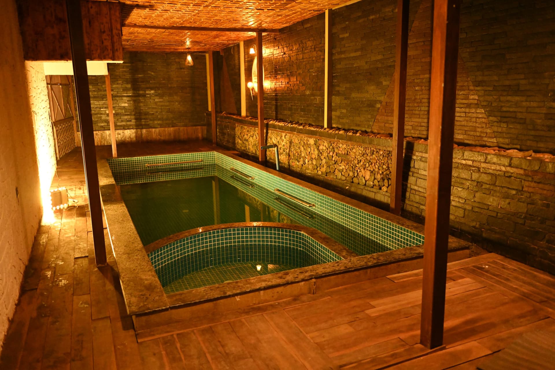 The private stone-clad pool at Palolem Heights, lamplit under a timber ceiling