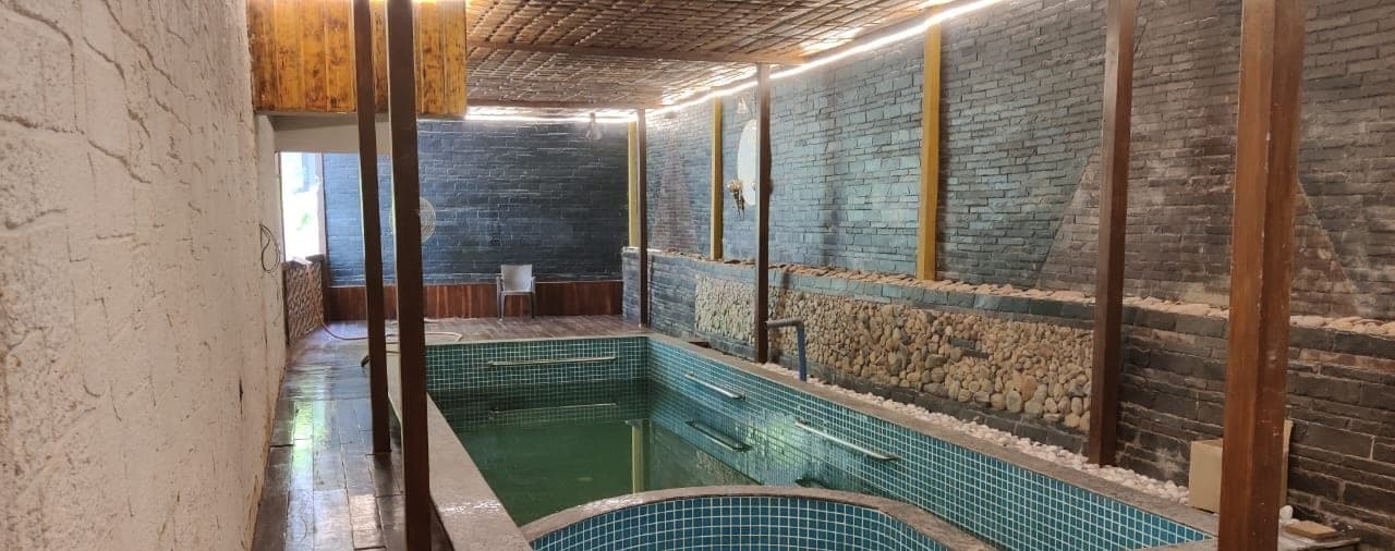 The private stone-clad pool at Palolem Heights under a woven ceiling