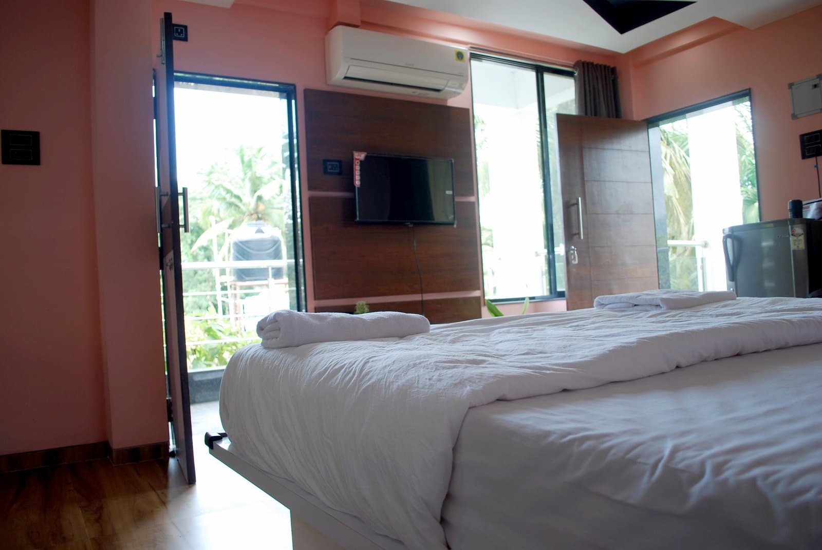 A suite with the balcony door open to the palms of Canacona